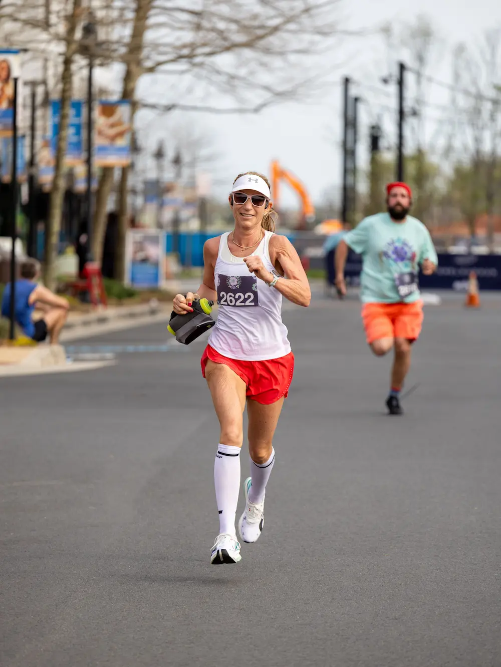 Woman running in marathon with water bottle.