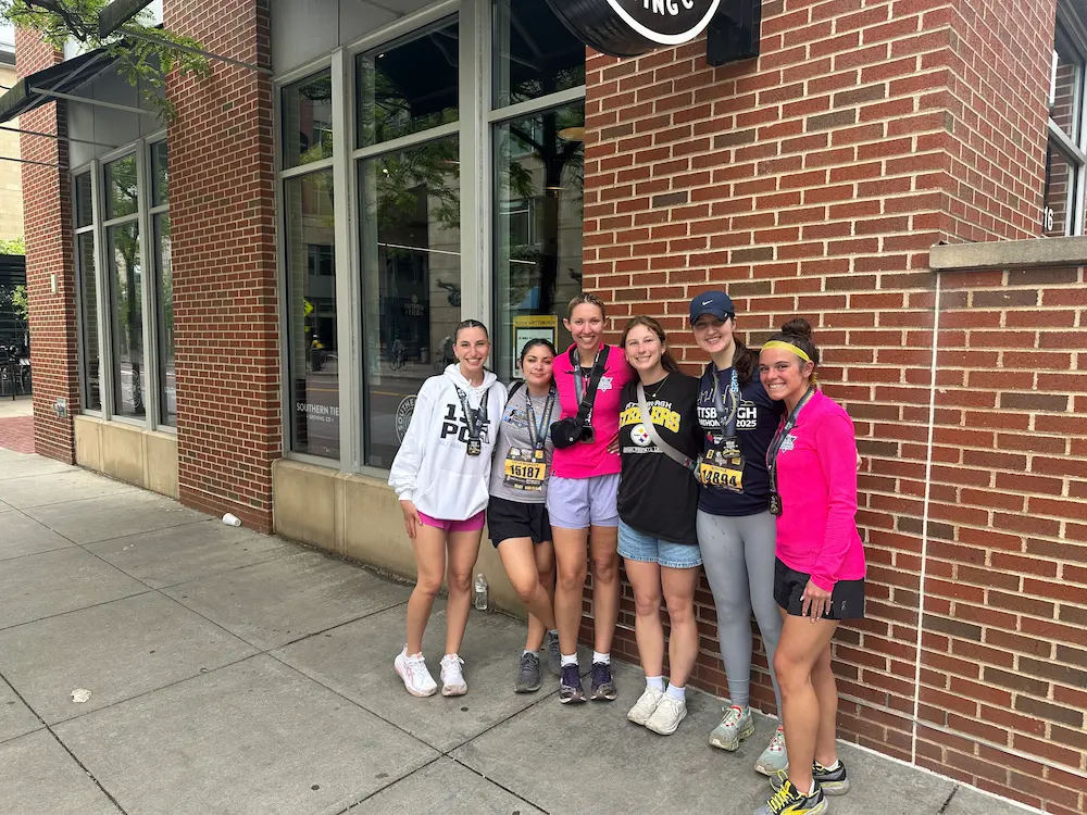 Group of women smiling after a race outside building.