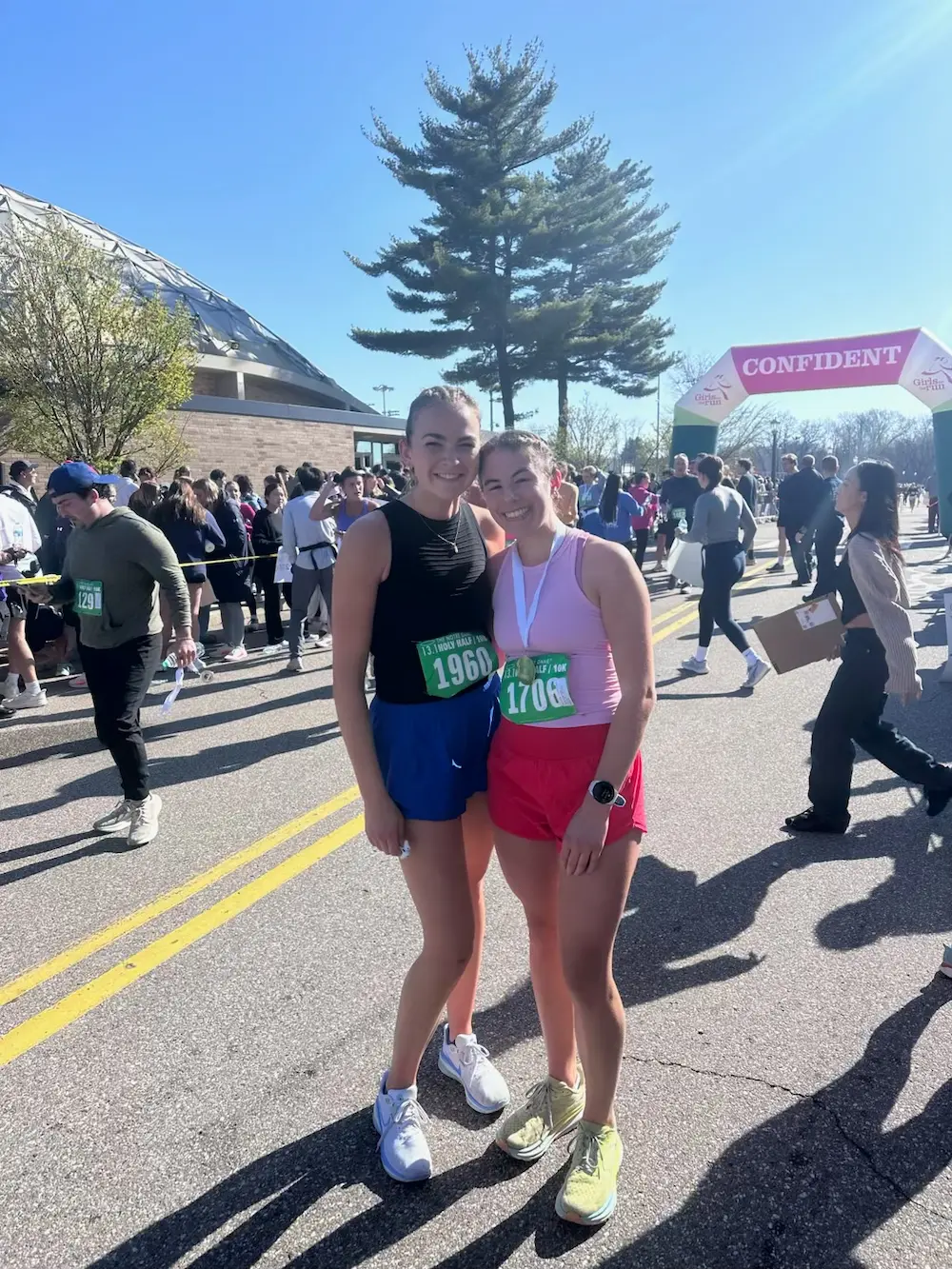 Two runners smiling at outdoor race event.