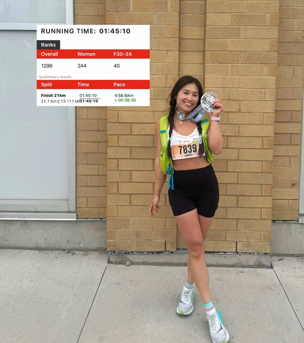Runner smiling with medal and race results board.