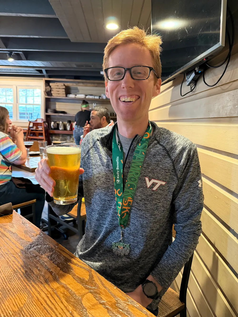 Smiling person with beer and medal in restaurant.