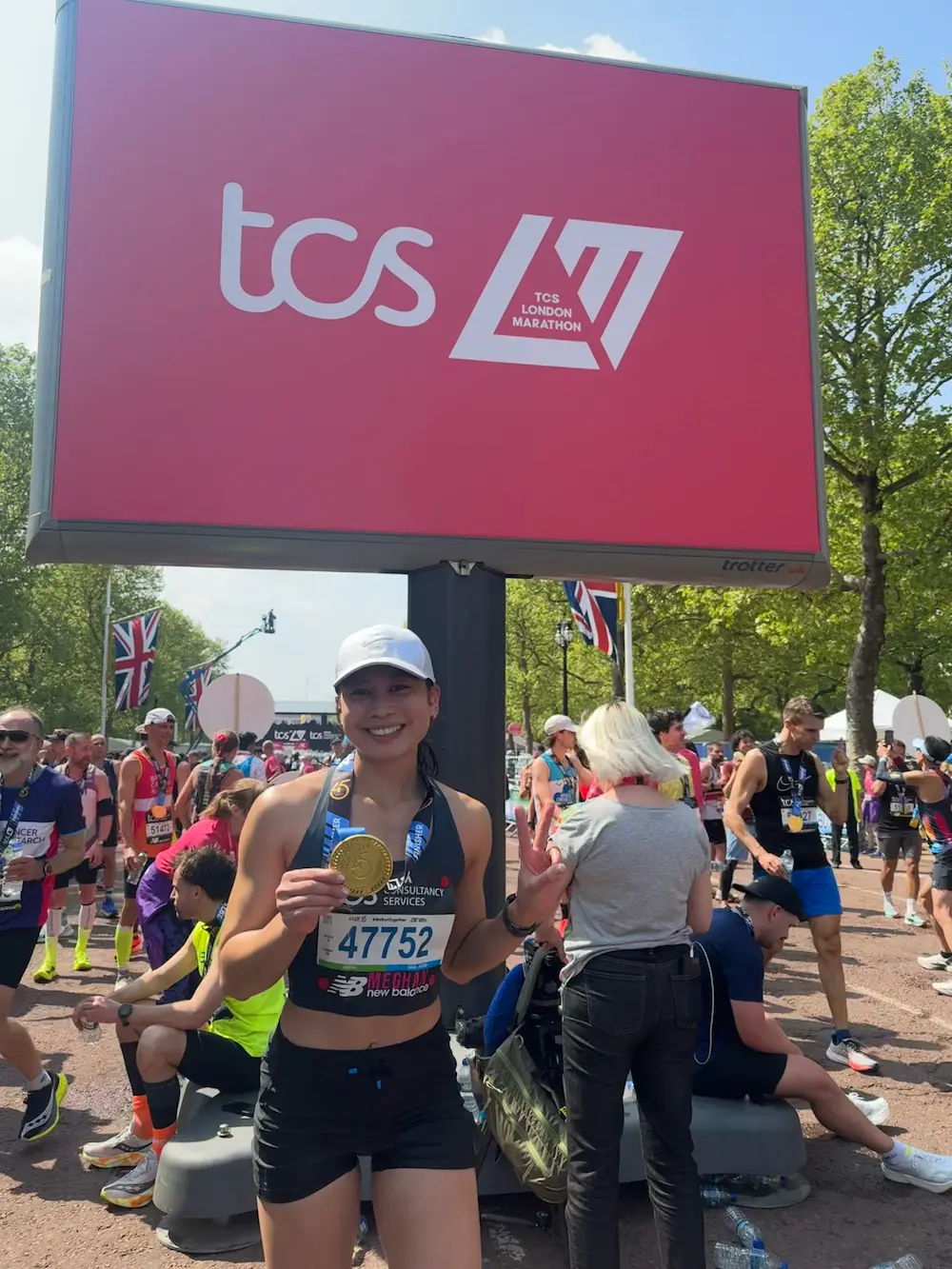 Runner smiling with medal at London Marathon finish line.