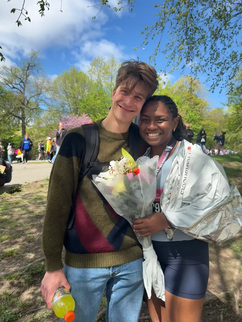 Smiling couple with flowers in a sunny park.