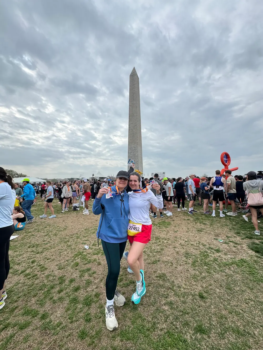 Marathon finishers at Washington Monument, cloudy sky.
