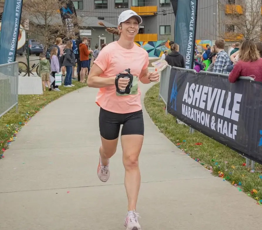 Woman running in Asheville Marathon smiling.
