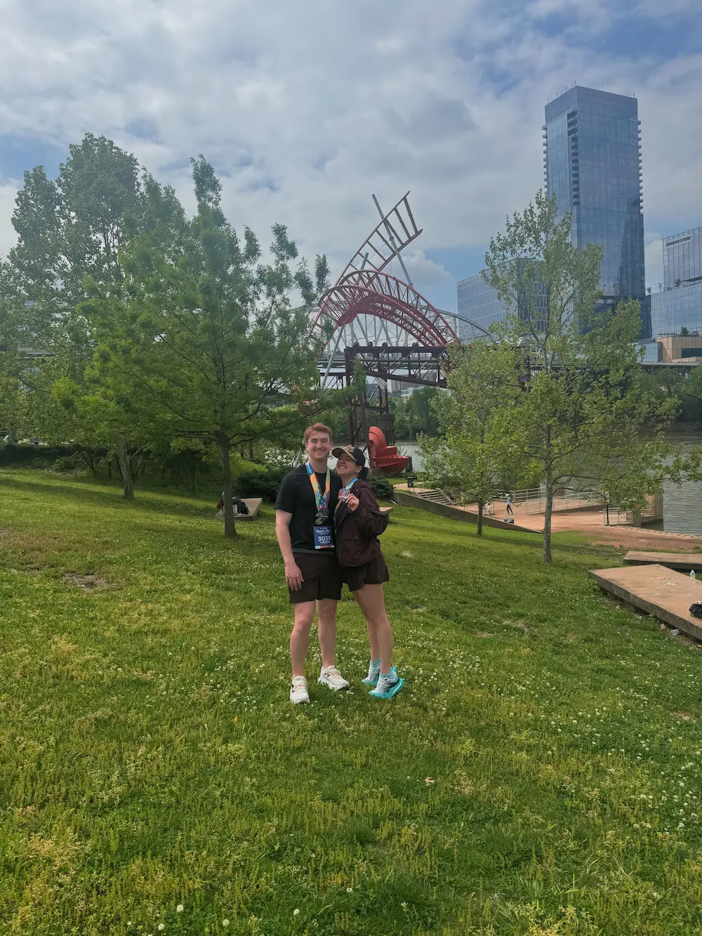 Two people standing in a park with sculpture background.