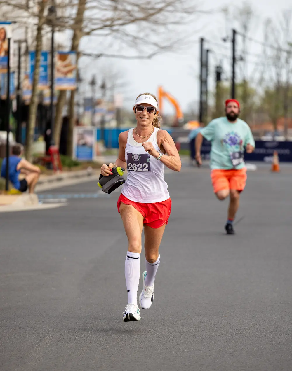 Woman running a marathon race on city street.