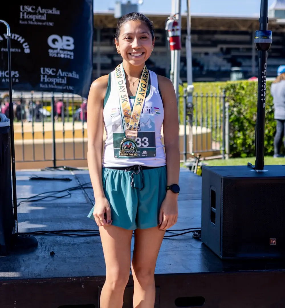 Smiling runner with medals after a race.