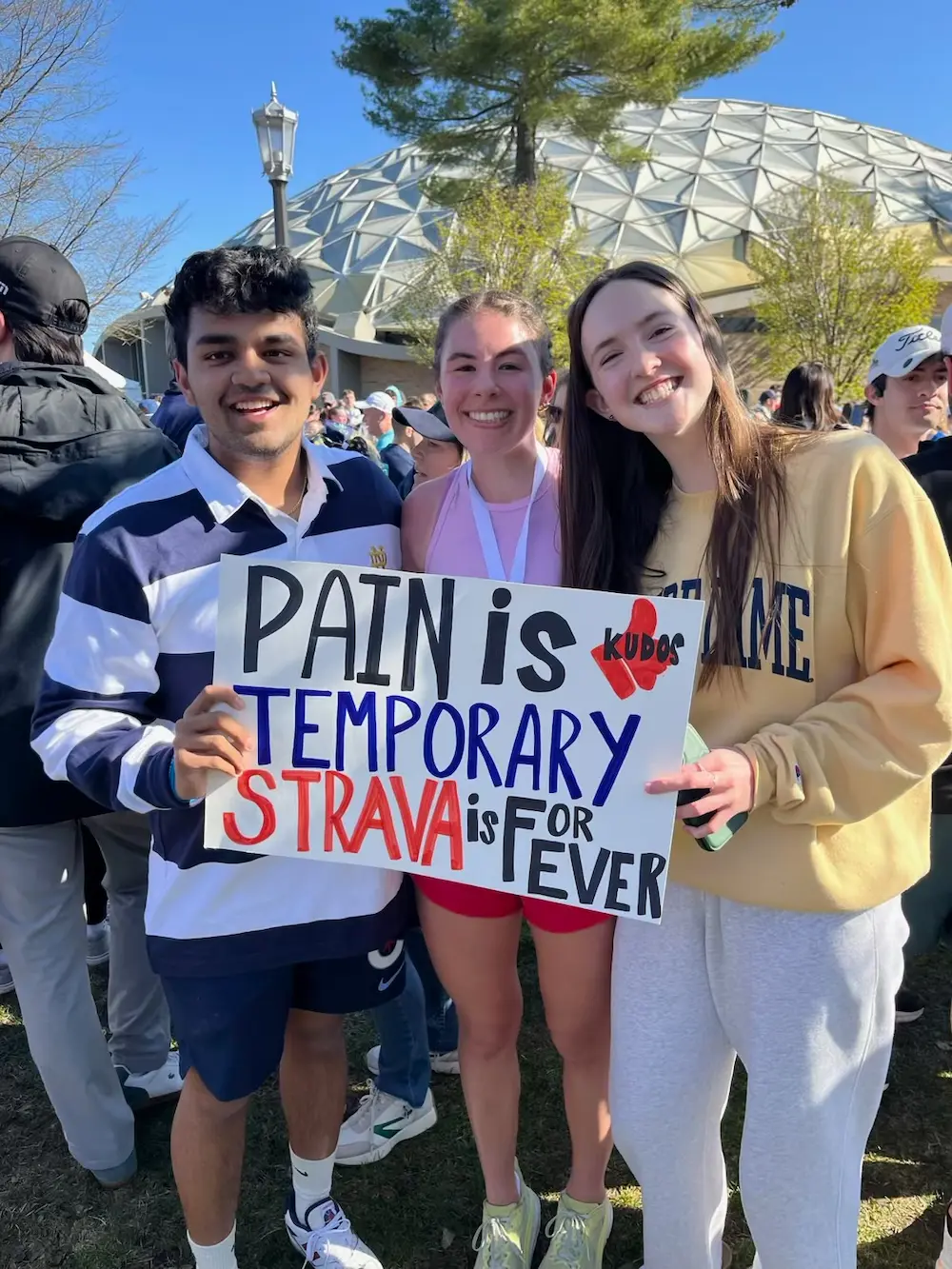 Three friends pose with motivational Strava sign.
