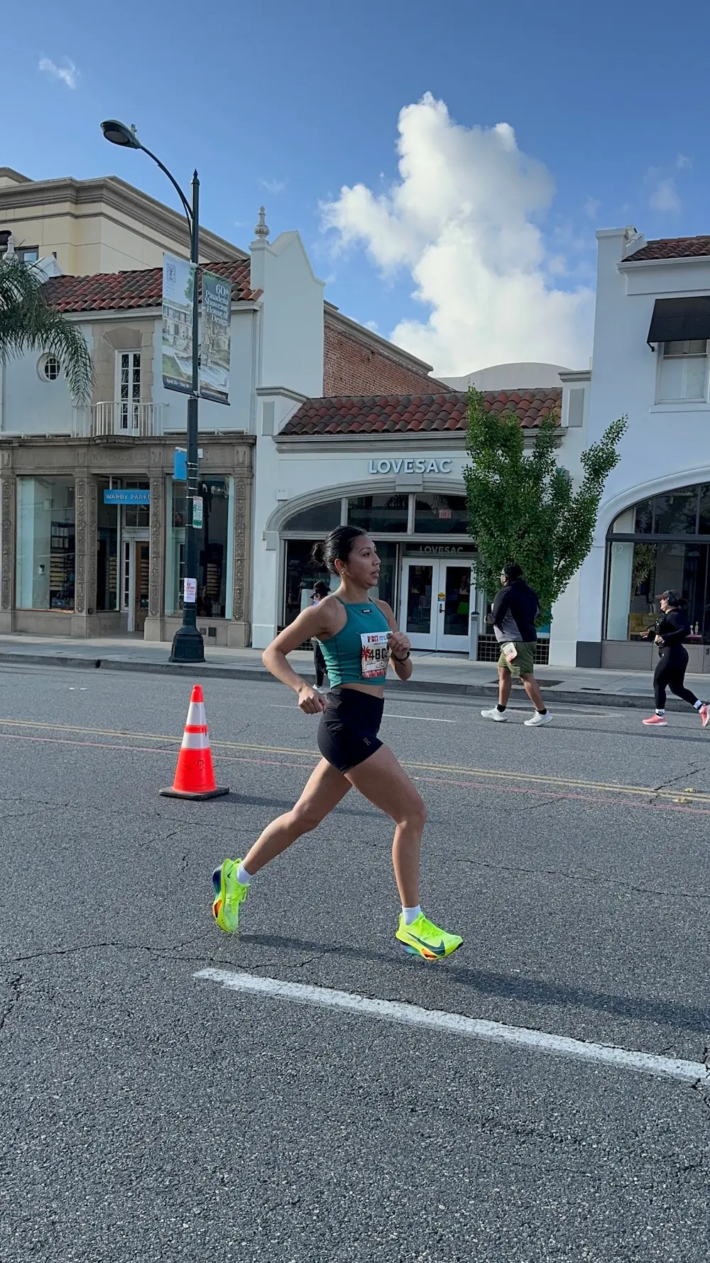 Woman running in street race past storefronts.