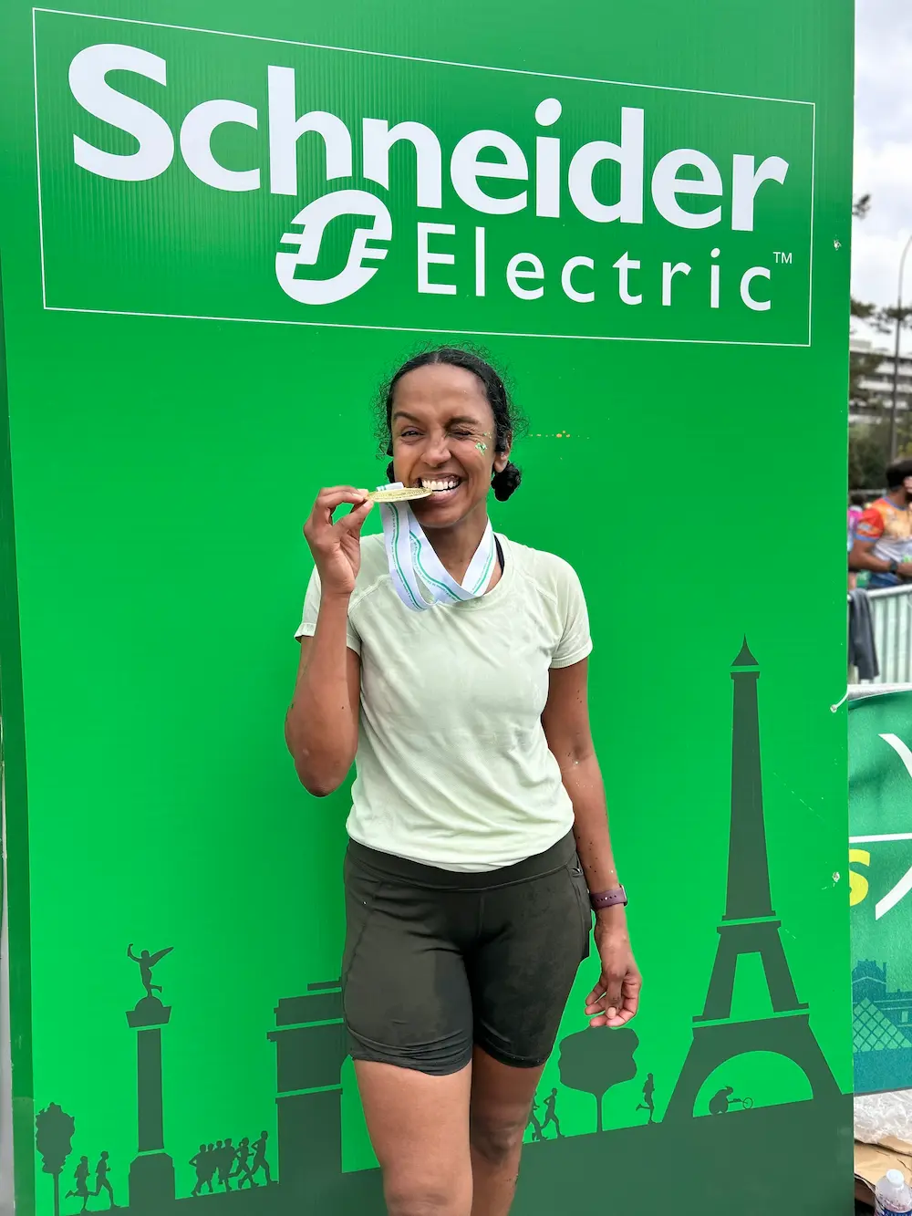 Runner celebrating with medal at Schneider Electric event.