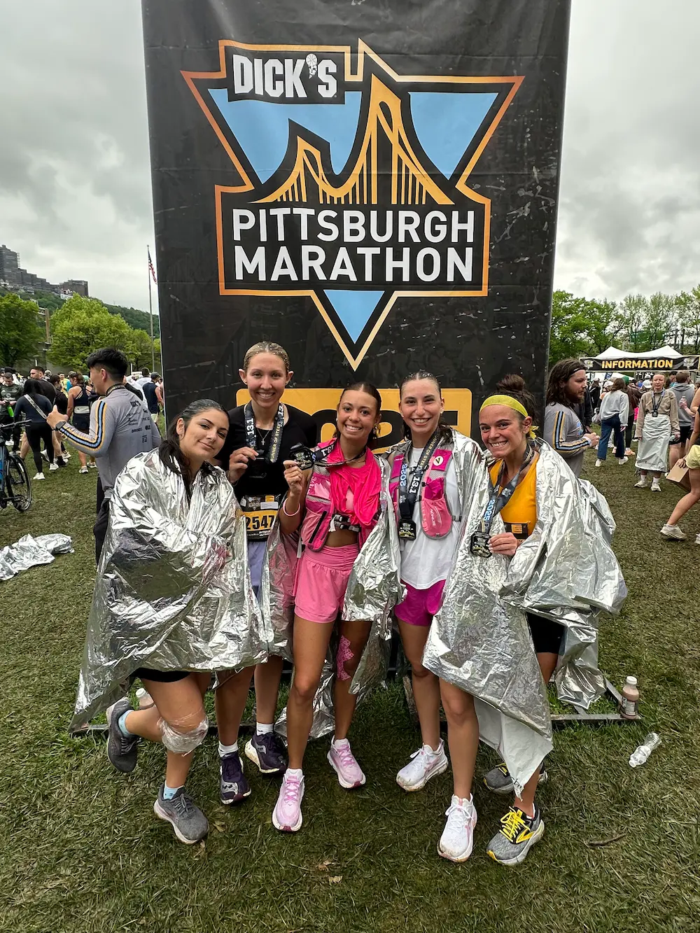Five runners pose at Pittsburgh Marathon finish line.
