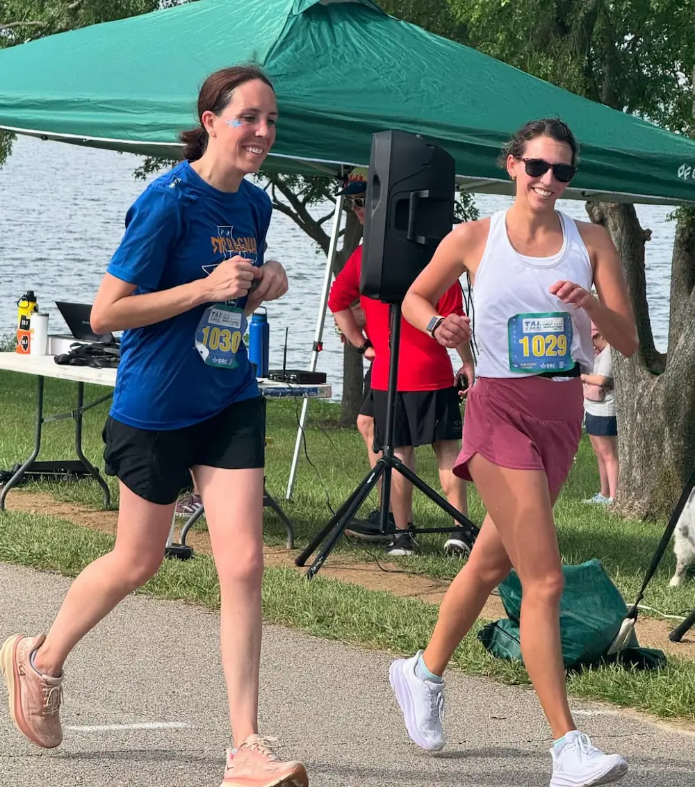 Two women running a race together smiling