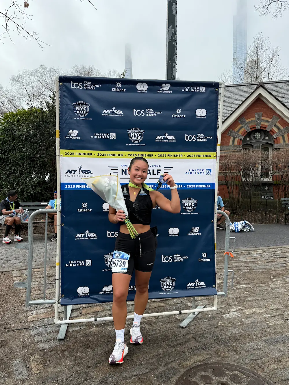 Runner celebrating NYC half marathon finish with flowers.