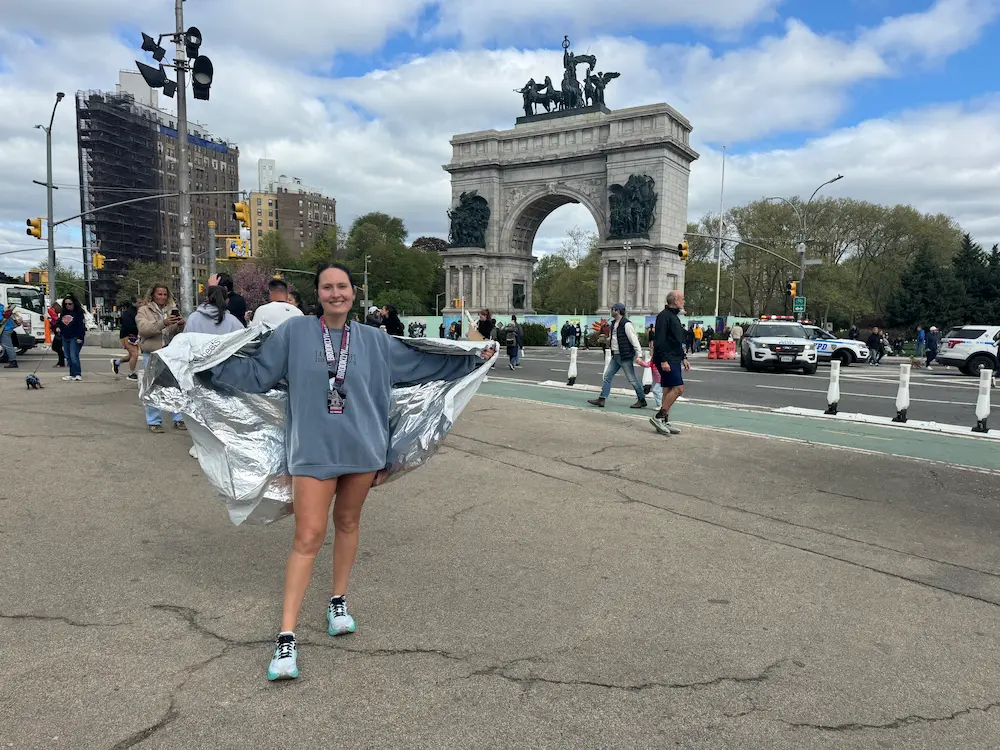 Runner with medal near monument in city street.
