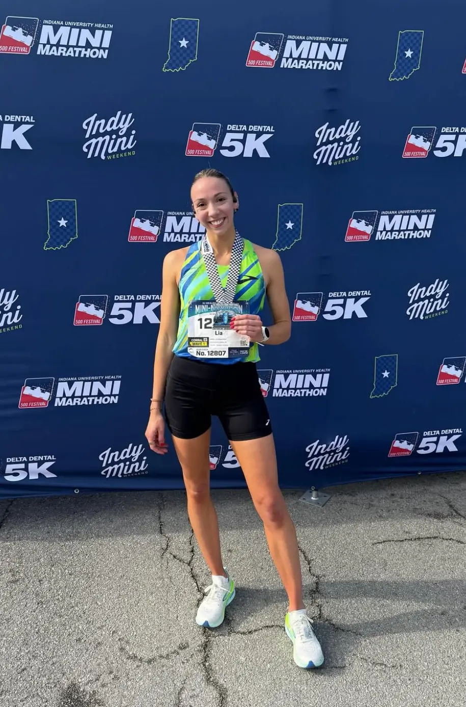 Runner smiles with marathon medal at Indy Mini.