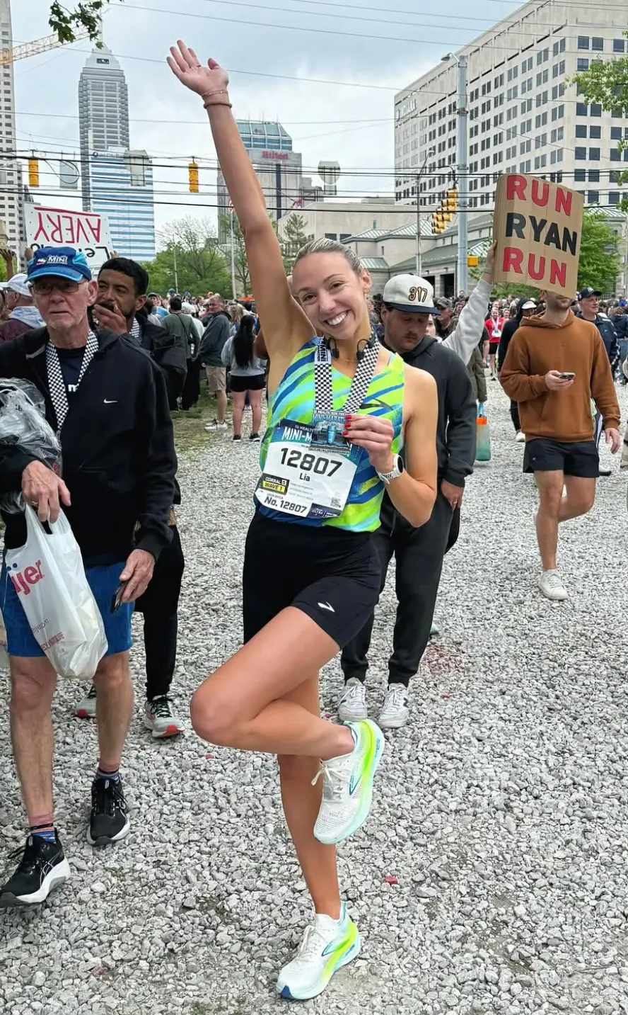 Smiling runner celebrates after race with medal.