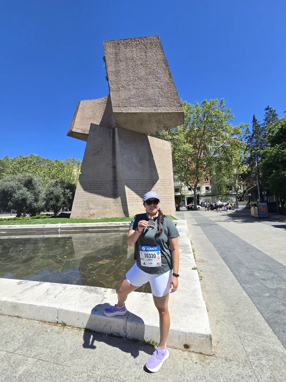 Runner celebrating with medal near city sculpture.