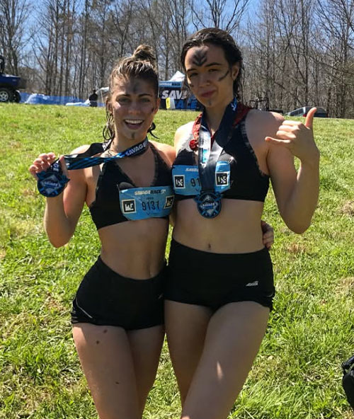 Two women posing with race medals outside.