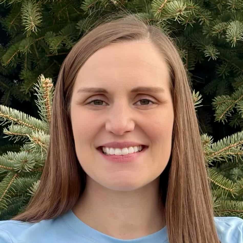 Smiling person in front of evergreen tree