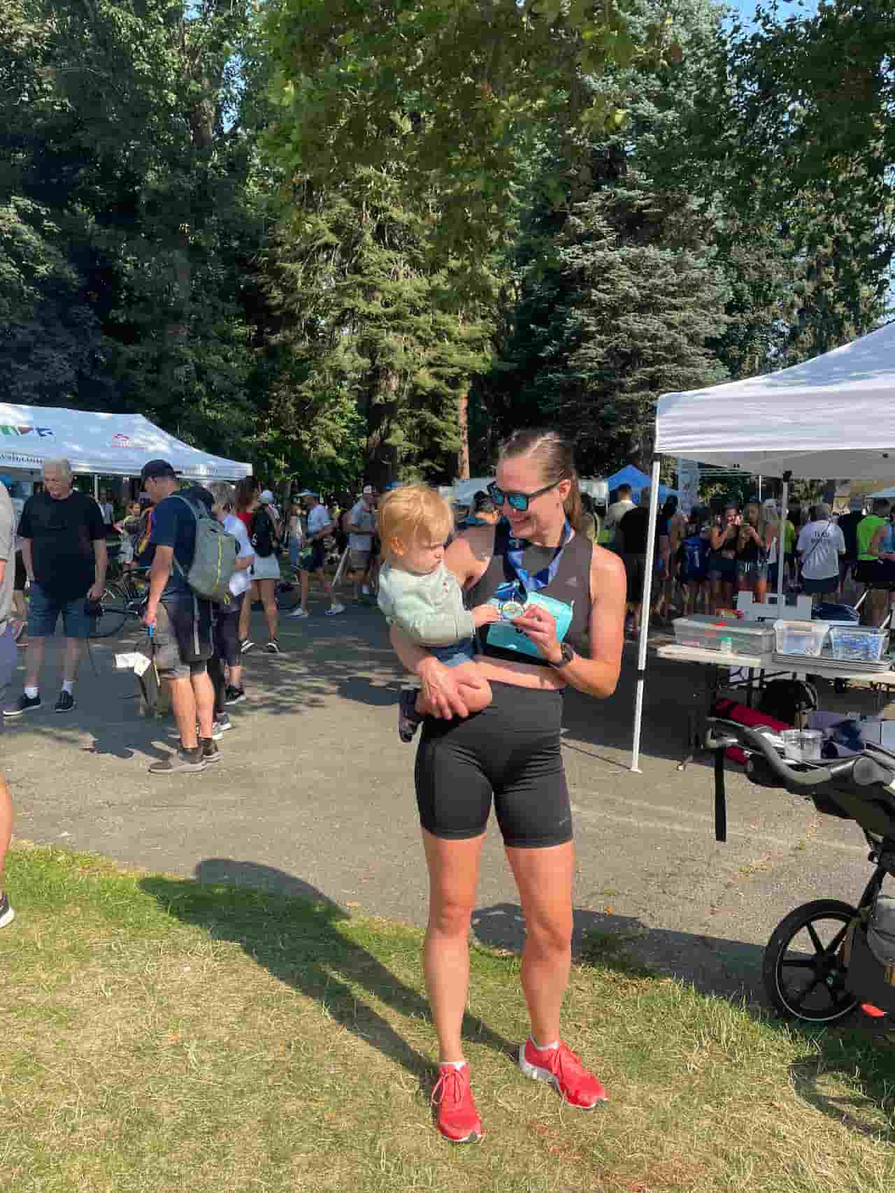 Woman holding child at outdoor event with tents.