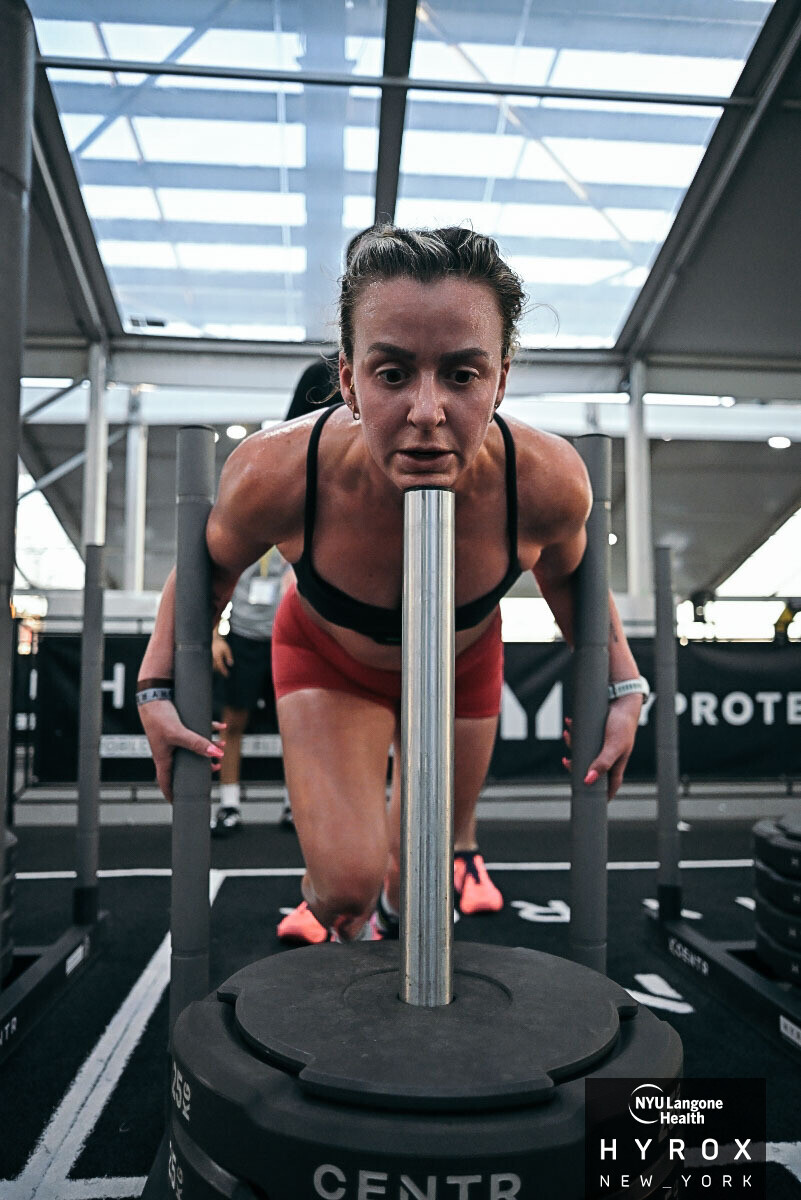 Woman pushing weighted sled during indoor fitness competition