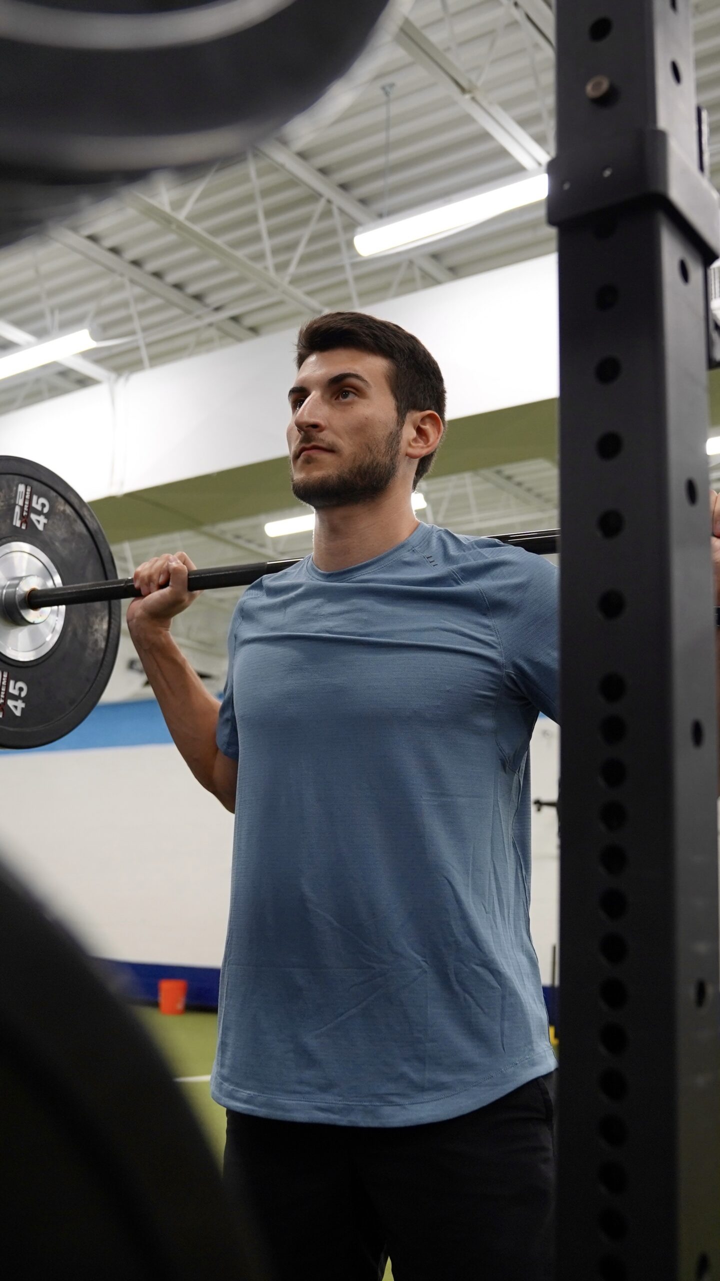 Man performing barbell back squat in gym