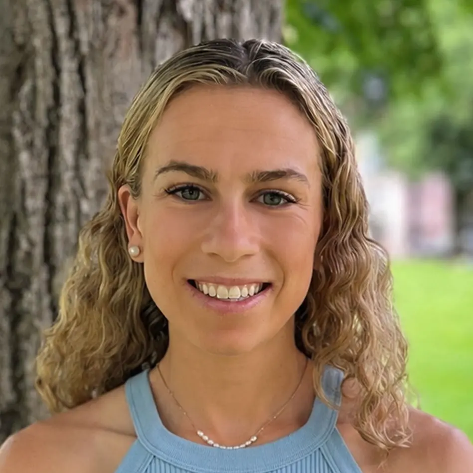Smiling woman outdoors by tree with green background
