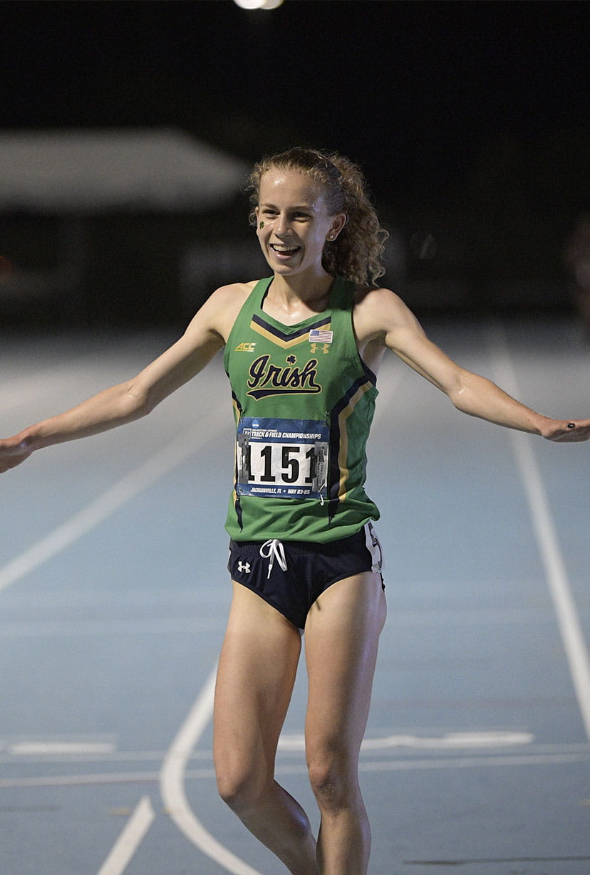 Female runner celebrating on track at night
