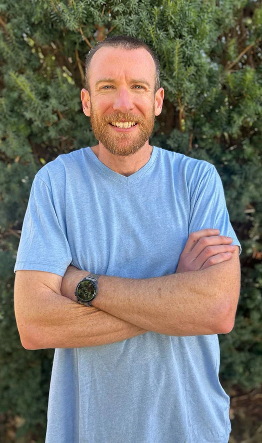Smiling bearded man in blue shirt standing outdoors