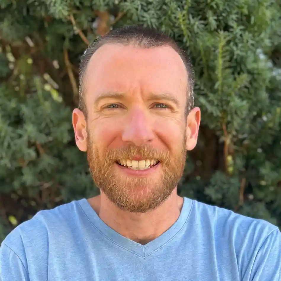 Smiling bearded man in blue shirt outdoors