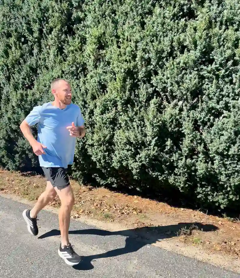 Man jogging beside a tall green hedge